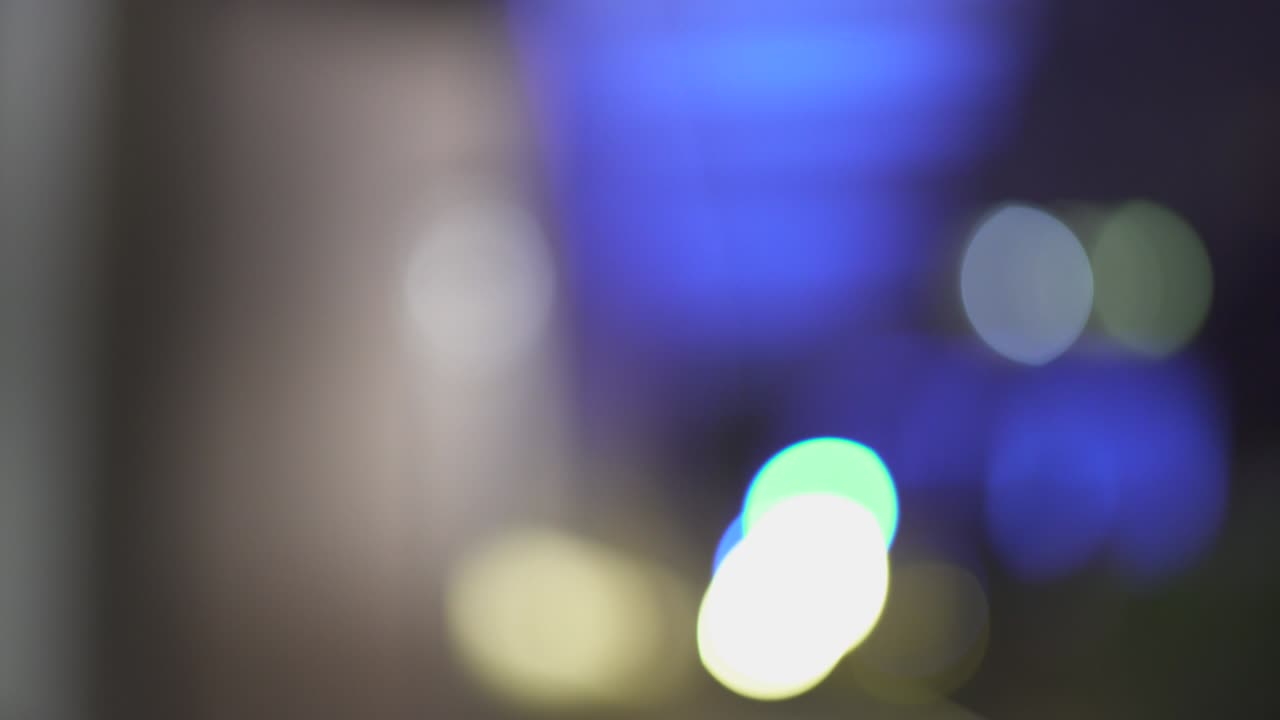 luces nocturnas desfocadas de la ciudad en el distrito comercial de parís. fondo de un rascacielos. color borroso bokeh de los edificios. seguimiento en. 4k uhd. azul y amarillo.
