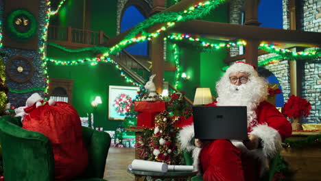 santa claus working on a laptop at a christmas office