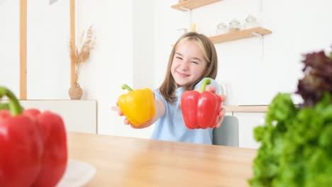the little girl is a vegetarian she is smiling and holding yellow and red peppers the little girl is a vegetarian she is smiling and holding yellow and red peppers cooking in the kitchen organically clean vegetables