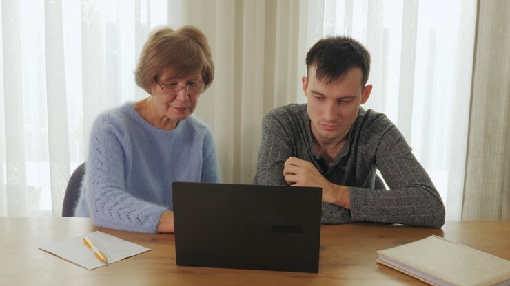 Donna anziana che insegna a un uomo a usare un laptop