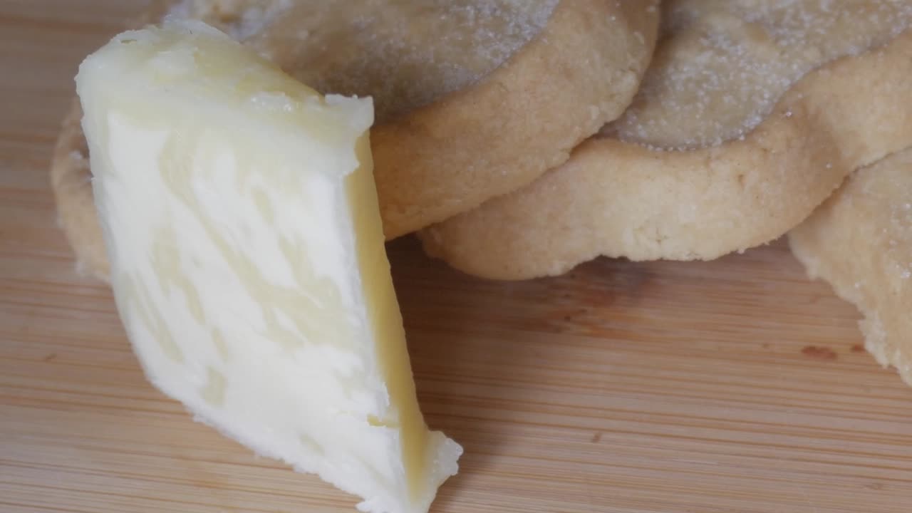 Shortbread biscuits served on a wooden board with a slice of butter placed beside them