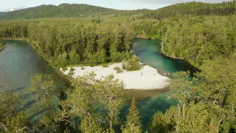 Beautiful-green-river-bend-revealed-in-the-wilderness-of-Alaska-with-a-boat-parked-on-the-shoreline