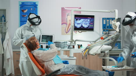 dentist in coverall examining x-ray image on tablet