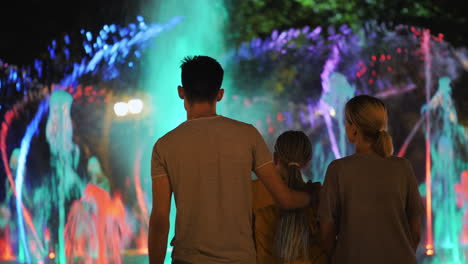 familia admirando la fuente de baile iluminada