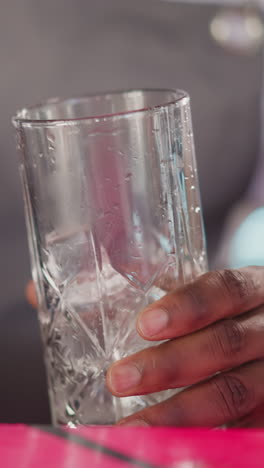 el camarero vierte cubos de hielo en el vidrio en el bar de primer plano. el camarero hábil prepara un cóctel refrescante para el invitado en el club. agua congelada para la bebida