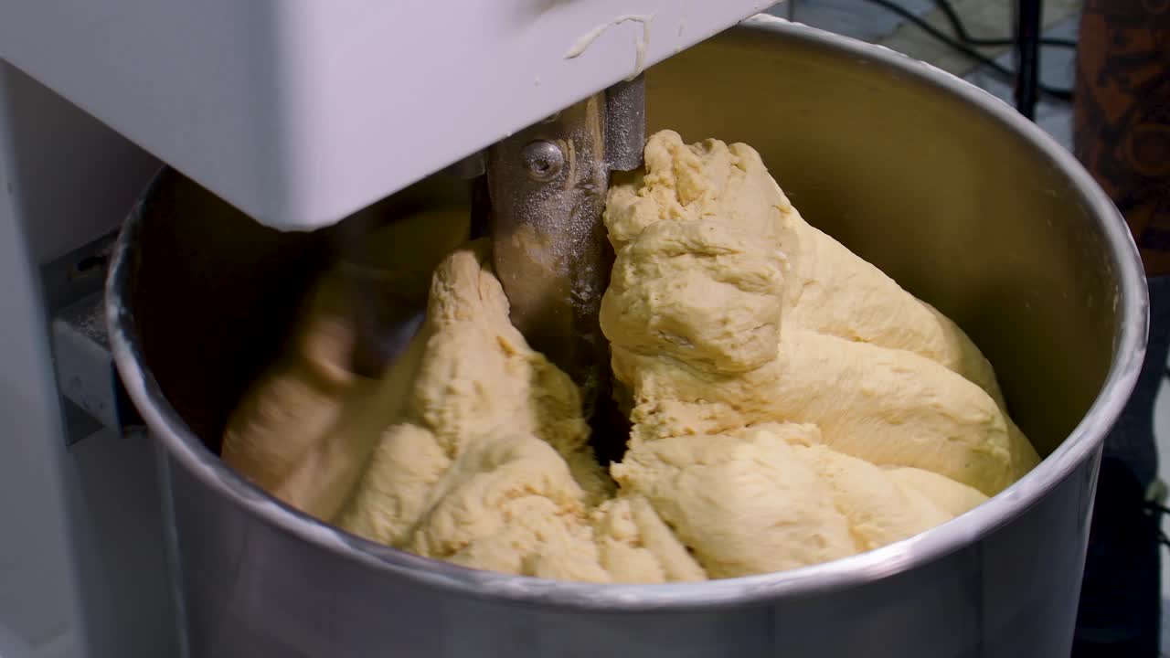 close-up focusing on the elastic, buttery texture and glossy surface of professional brioche dough as it reaches full gluten development in a spiral mixer