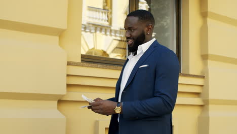 Smiling-afro-man-counting-money-outside