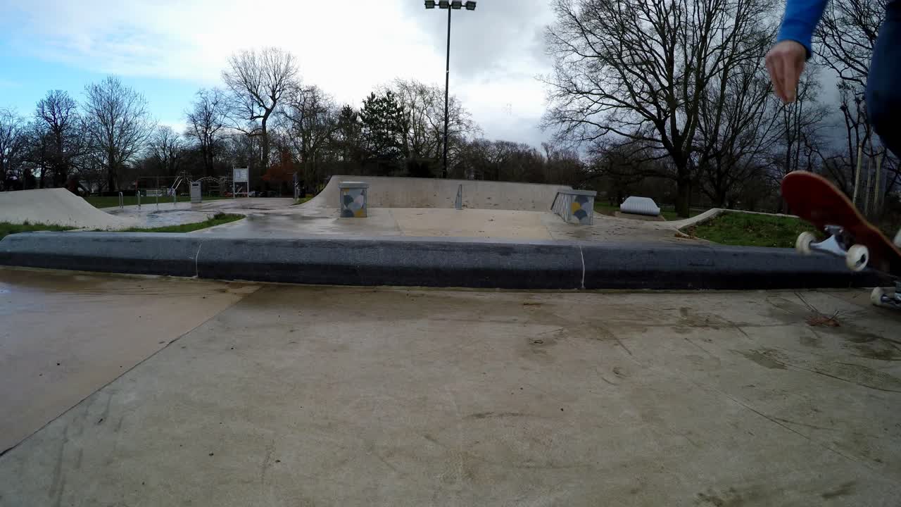 Seorang pemain skateboard terlihat melempar papan skateboard-nya ke tanah saat ia melompatinya, lalu meluncur dan melaju pergi.
