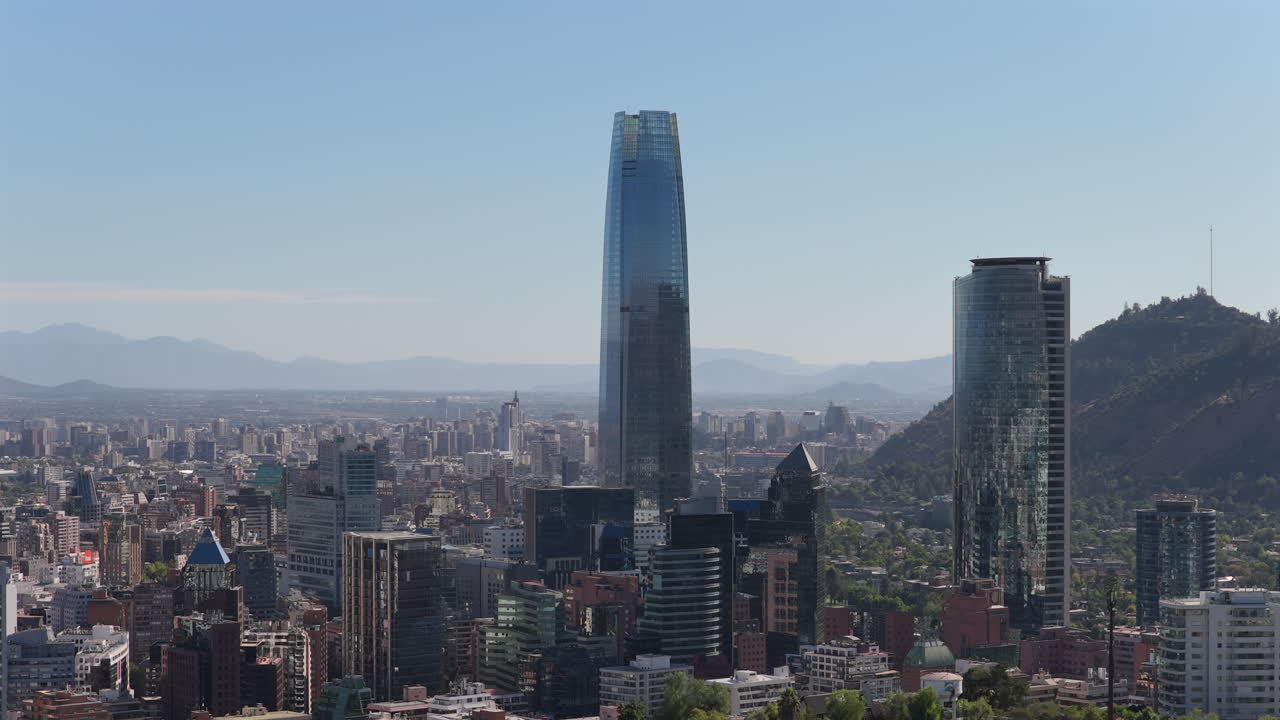 Costanera Center, edifici per uffici Titanium e il quartiere finanziario di Santiago in un pomeriggio estivo, con il centro città e il centro storico sullo sfondo, e la collina di San Cristobal sulla destra. Ripresa aerea lenta.