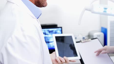 dentista y asistente dental trabajando en una tableta digital