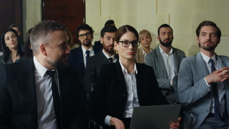 close-up view of the audience at a business conference listening to the speaker, then caucasian businesswoman rises her hand and asks a question