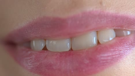 extreme closeup on a lips of a young adult woman with a perfect white healthy smile