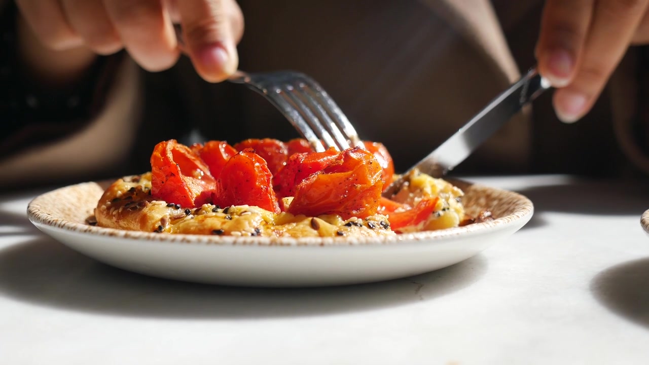 Person isst geröstete Tomatentarte in einem Café