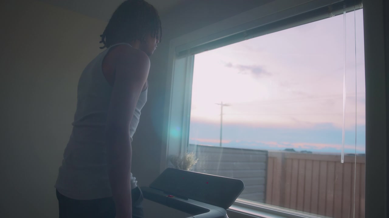 Uomo che cammina su un tapis roulant a casa con vista tramonto