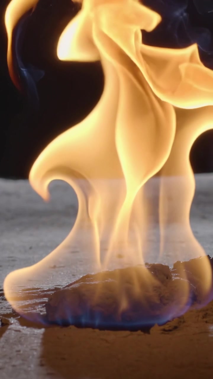 Video verticale: Accensione di una pozza di carburante, che invia una base blu e lingue ambrate sul cemento, fumo.