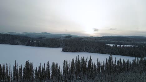 Dreamlike-Winter-View:-A-Scenic-Reverse-Pan-Right-Aerial-Shot-of-Snowy-Fir-Trees-Near-Latremouille-Lake-and-Little-Fort-Highway-24-on-a-Cloudy-Day