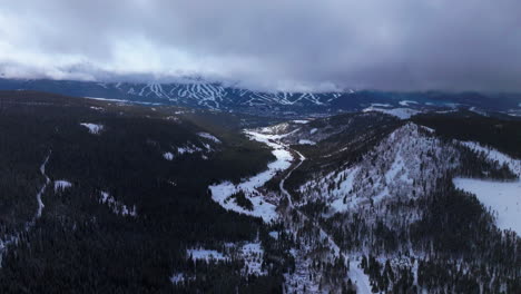 Ten-Mile-Breck-Peaks-Breckenridge-Ski-resort-town-Vail-Epic-Ikon-Pass-aerial-drone-landscape-cloudy-fog-gray-winter-morning-ski-trail-runs-Summit-County-Tiger-fork-road-Rocky-Mountains-down-motion