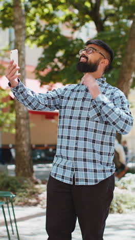 Blogger-Indio-Tomando-Selfie-En-Videollamada-De-Teléfono-Inteligente-En-Línea-Con-Suscriptores-En-La-Calle-De-La-Ciudad