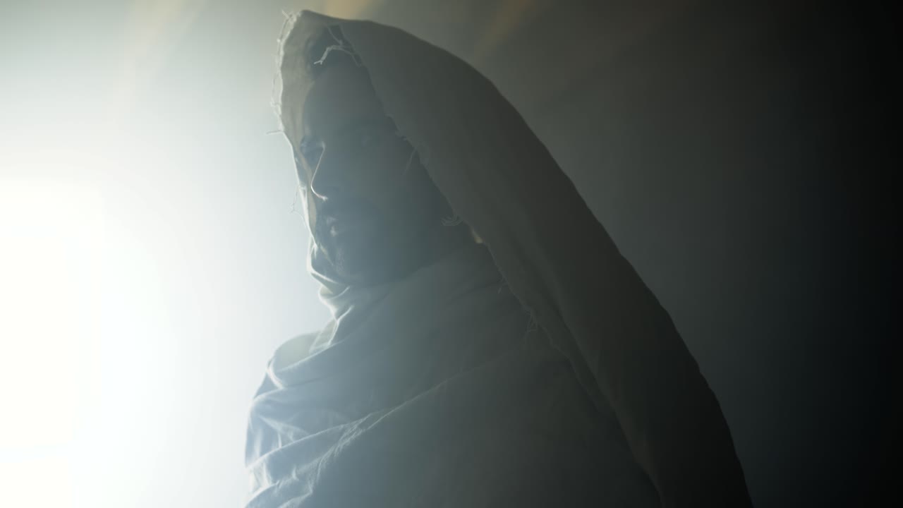 The resurrected Jesus Christ standing inside the tomb in bright, dramatic, glowing, holy light as representation of the Easter Sunday resurrection in cinematic slow motion.