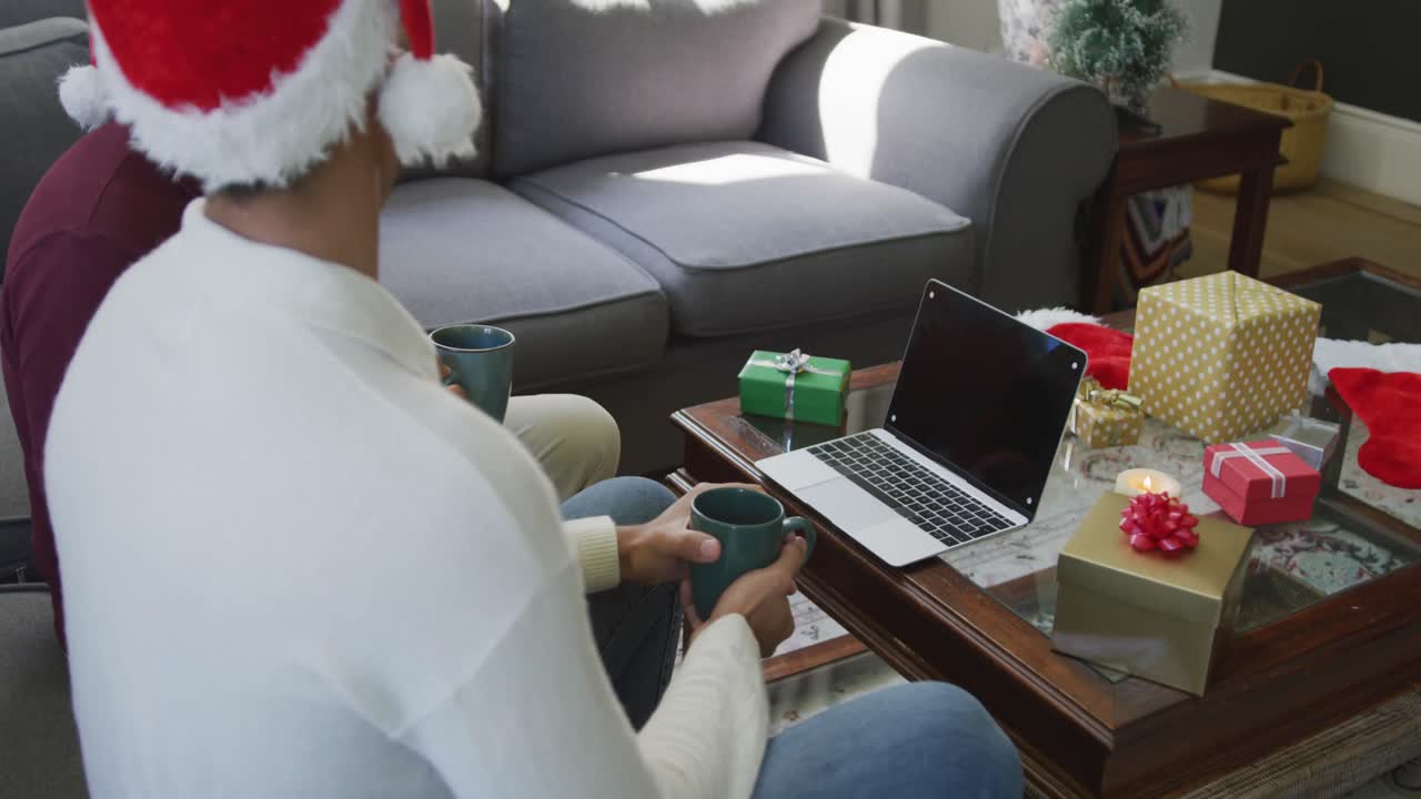 padre e hijo con sombreros de santa tomando café mientras hacen una llamada de video de navidad en casa