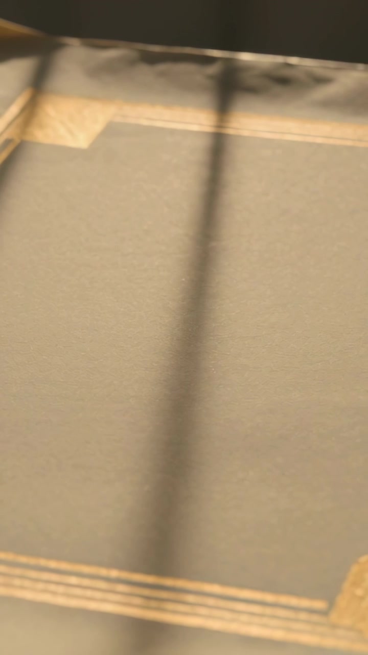 Vertical video: Shifting cam showing pale cover on bed to show gold corner, moving vertical shadow