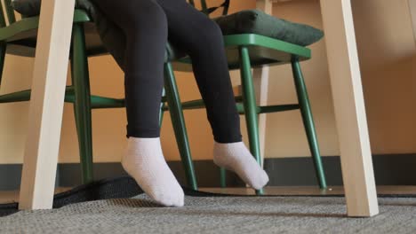 child sitting on a chair with feet hanging down