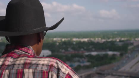 Black-man-with-cowboy-hat-looking-out-over-balcony