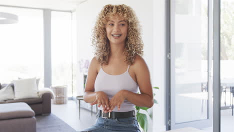 At-front-door,-young-biracial-woman-talking-on-video-call-at-home