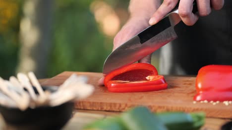 young man cutting peppers on a wooden board in his garden close up