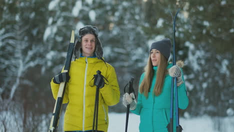 full length portrait of active young couple enjoying skiing in snowy winter forest, focus on smiling woman in front, copy space