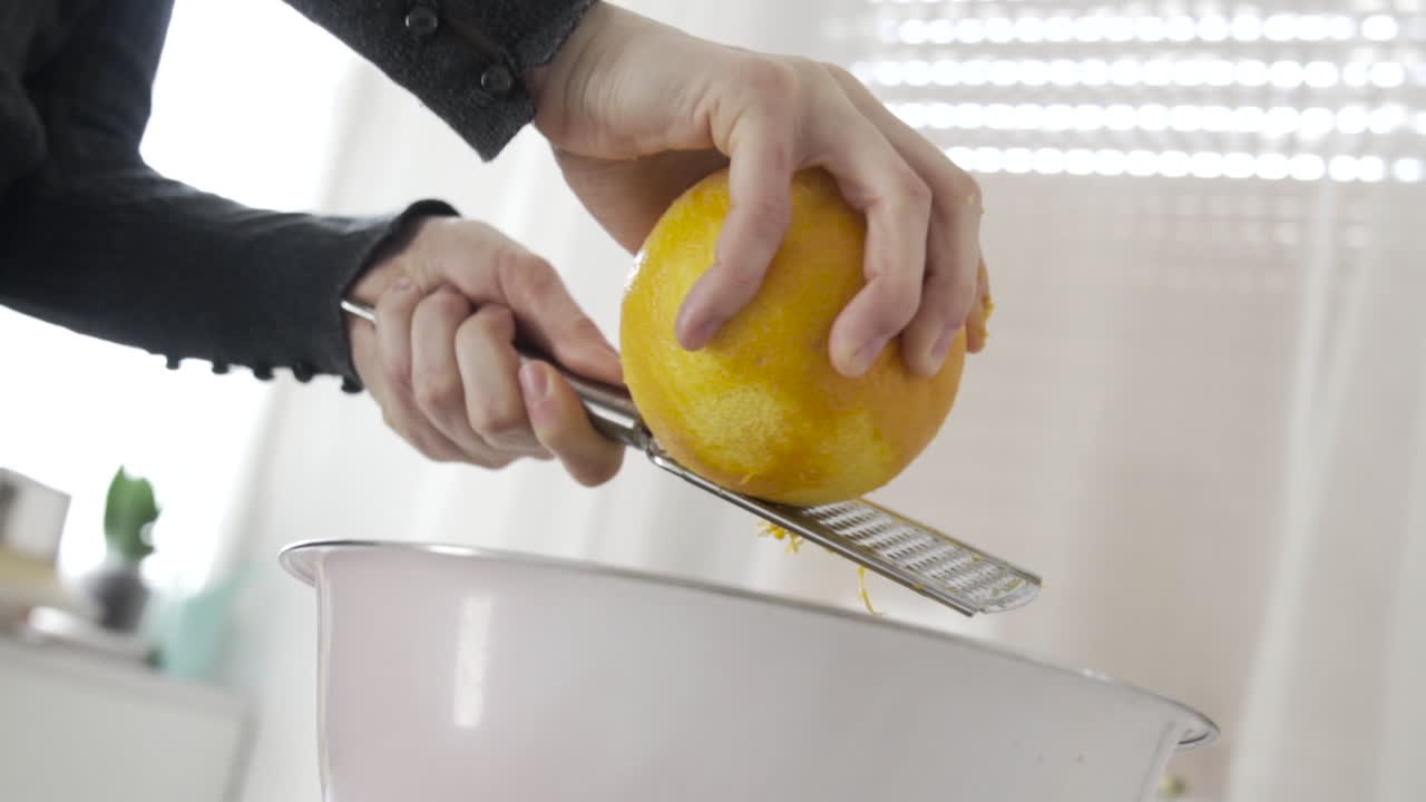 Slow motion rasping peeling orange skin off in a bowl 