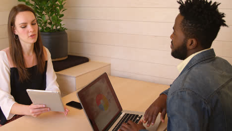 Young-cool-mixed-race-business-team-planning-and-sitting-with-laptop-at-desk-of-modern-office-4k