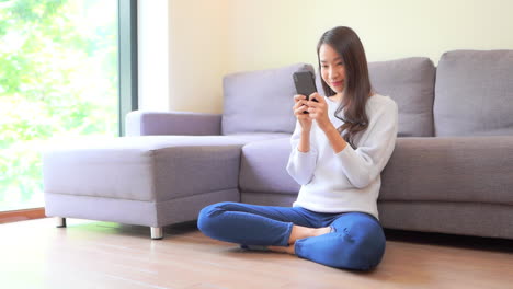 Joven-Mujer-Bastante-Asiática-Leyendo-Mensajes-De-Texto-En-El-Teléfono-Inteligente-En-La-Privacidad-Del-Hogar