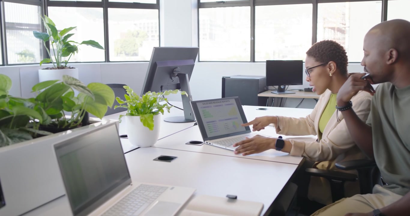 Colleghi africani che lavorano alla scrivania, dopo che un uomo osserva, si china e indica con una penna i dati sul laptop