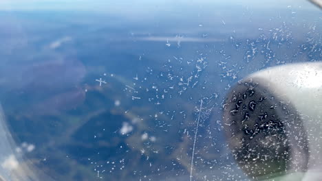 frozen droplet particles on airplane window, outside the window, part of a jet engine