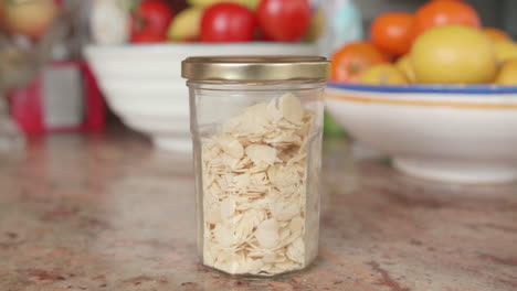 Sliced-or-flaked-almonds-in-a-glass-jar-on-a-kitchen-table