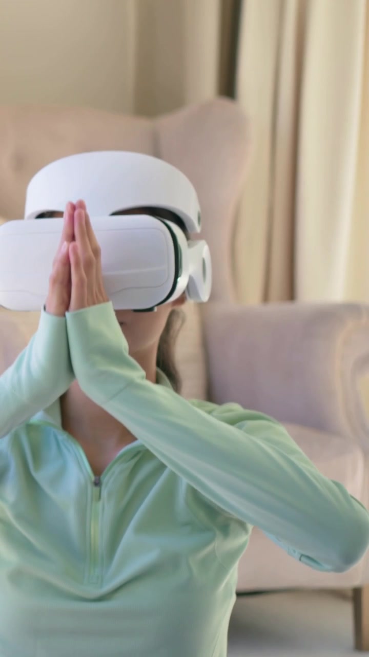 Video verticale: Donna in top verde che, seguendo un'indicazione guidata, abbassa le braccia e respira a casa con la VR.