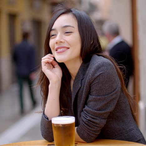 Friendly-young-woman-sitting-enjoying-a-beer