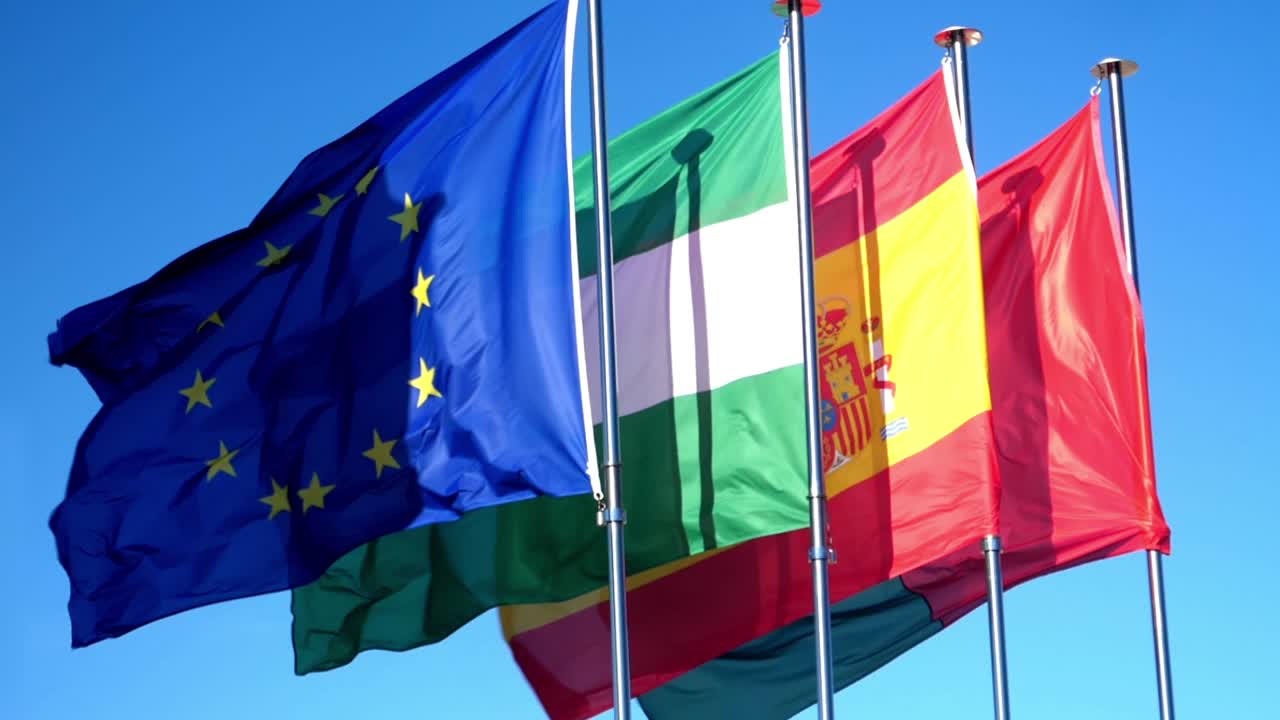 Bandiere dell'Unione Europea, dell'Andalusia e della Spagna che sventolano contro il cielo azzurro