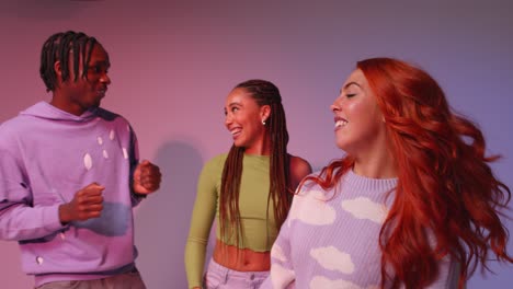 studio shot of young gen z friends dancing at club against pink background 3