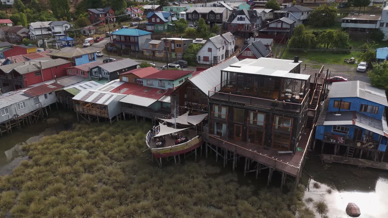 Aerial view capturing colorful palafitos, traditional wooden stilt houses in Castro, Chiloe Island, Chile, highlighting unique architecture. circle dolly