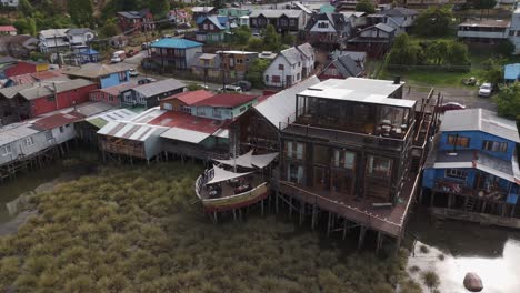 aerial view capturing colorful palafitos, traditional wooden stilt houses in castro, chiloe island, chile, highlighting unique architecture. circle dolly
