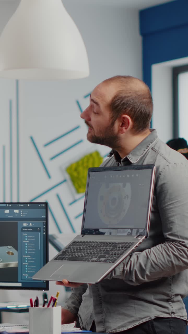 Vertical video Man project supervisor holding laptop and pointing on display