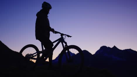 a mountain biker is standing on top of a ridge during sunrise