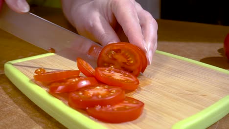 Knife-cuts-tomato-on-wooden-board-Slow-motion-with-rotation-tracking-shot.