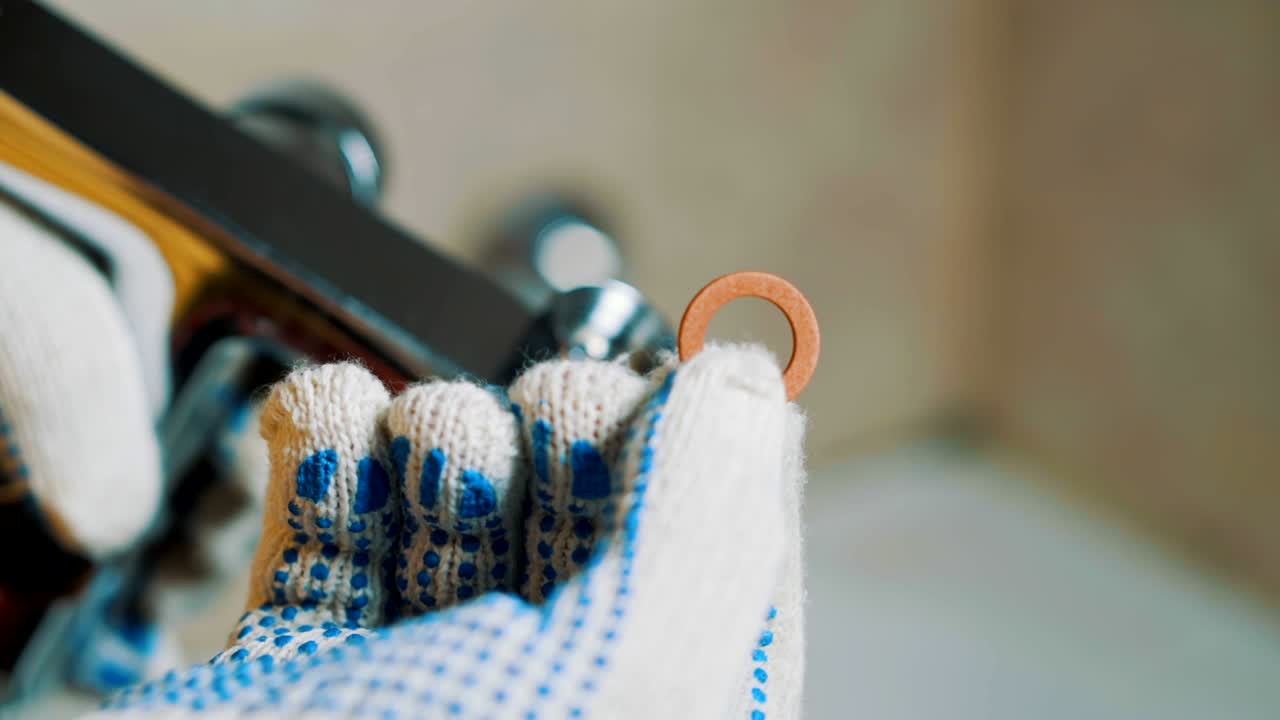 근접 장갑을 쓴 배관공의 손이 프에 가스켓을 설치합니다.