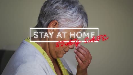 animation of stay at home stay safe text over worried senior woman at home