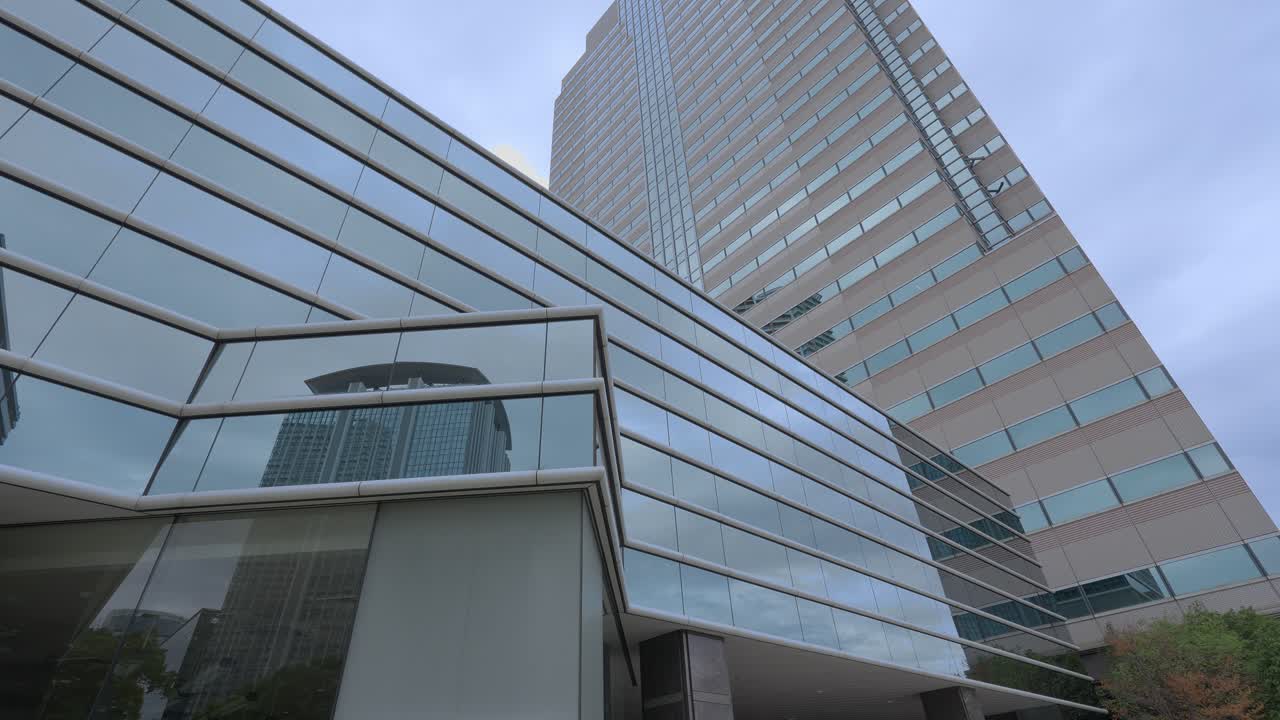 A low-angle shot of a tall, modern skyscraper with a reflective glass facade against an overcast sky