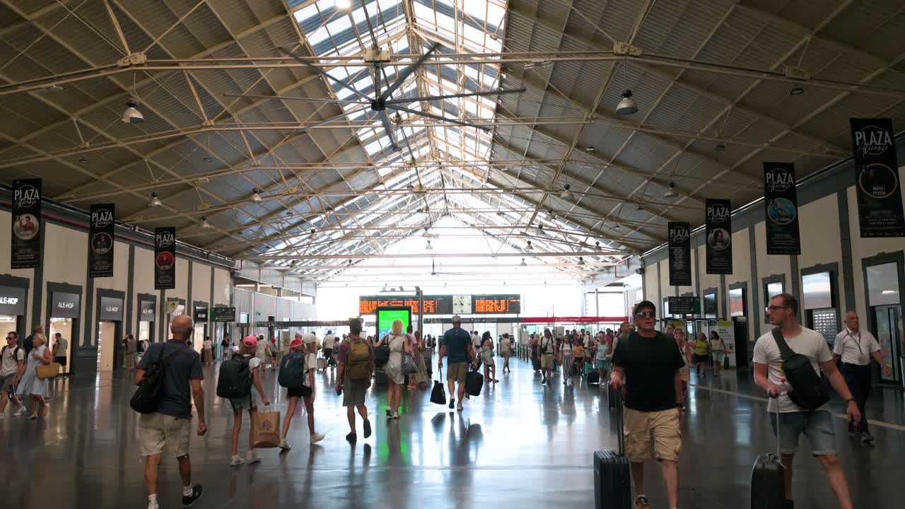 Wide shot of passengers moving through the main terminal hall at Alicante train station in Alicante, Spain