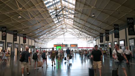 wide shot of passengers moving through the main terminal hall at alicante train station in alicante, spain